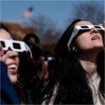 Two people wearing special glasses for a solar eclipse look skyward.